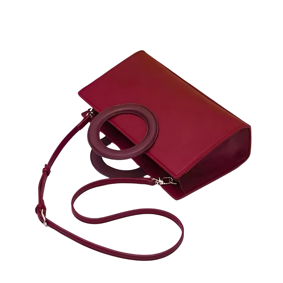 Die Tasche Ruby aus hochwertigem strukturiertem Leder in auffälligem Rot, abgebildet auf einem neutralen Hintergrund. Die Handtasche zeigt ihre elegante Form und Details wie den Magnetverschluss, der die Tasche schließt. Die Tasche kann als Schulter- oder Umhängetasche getragen werden und ist ideal für besondere Anlässe wie Hochzeiten oder Events.