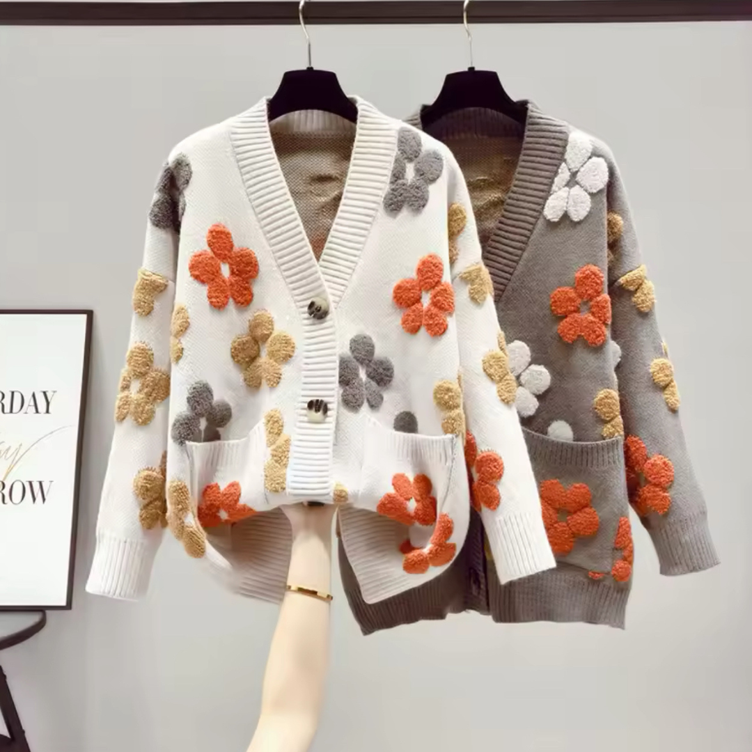 Produktfoto des eleganten Cardigans Flowers in Beige und Grau. Der Cardigan zeigt einen lockeren, westlichen Stil mit langem Ärmel und V-Ausschnitt, gefertigt aus weichem, hochwertigem Strickmaterial. Die entspannte Passform und die herbstliche Eleganz machen ihn ideal für die kühleren Tage und vielseitig kombinierbar mit verschiedenen Outfits.