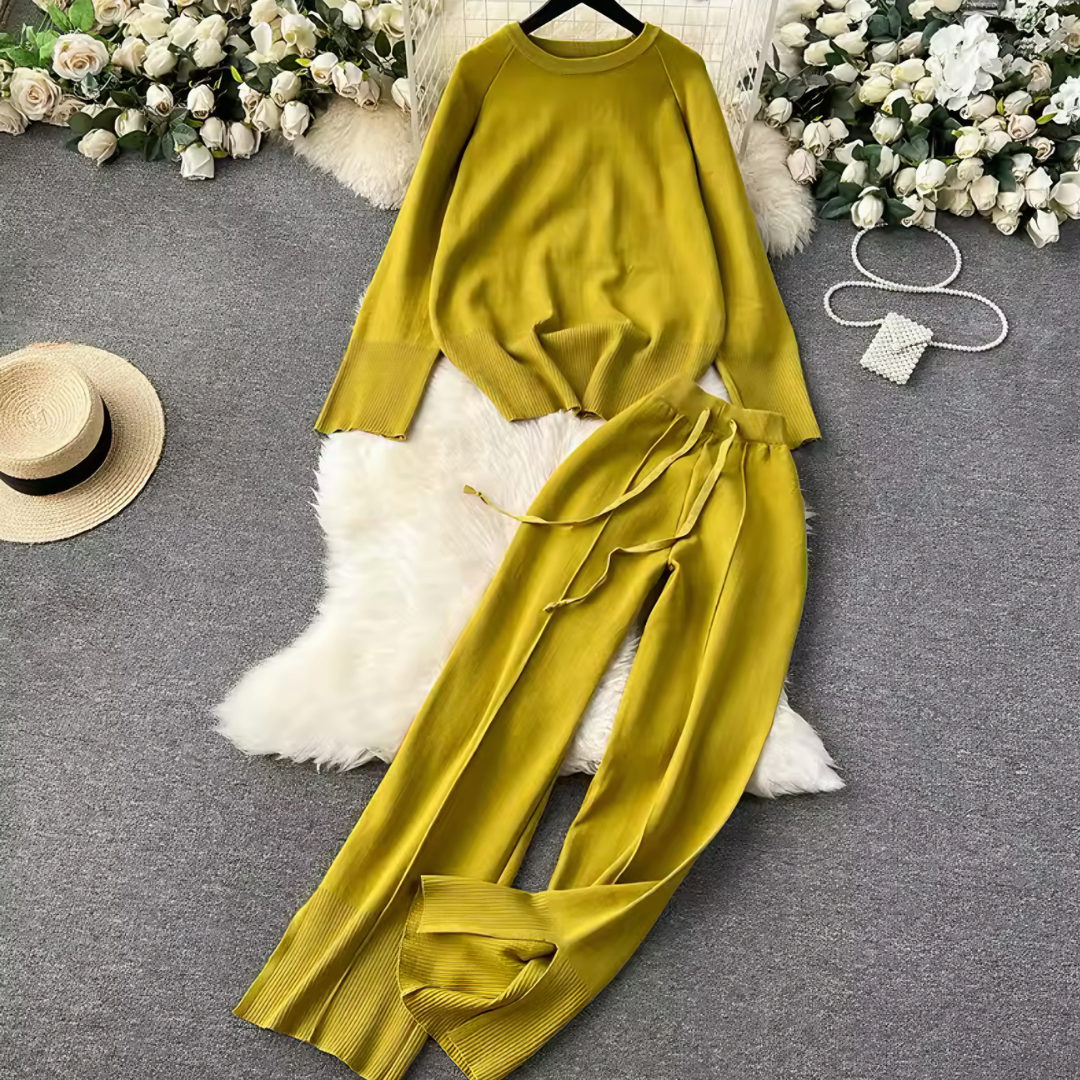 Cozy Set Noemi in Gelb, bestehend aus einem lässigen Pullover mit O-Ausschnitt und einer weit geschnittenen Hose, in Produktfoto. Das elegante, gestrickte Material bietet luxuriösen Komfort und Wärme, während das lockere Design eine stilvolle Silhouette schafft. Ideal für den Alltag, Büro-Style oder entspannte Tage zu Hause.