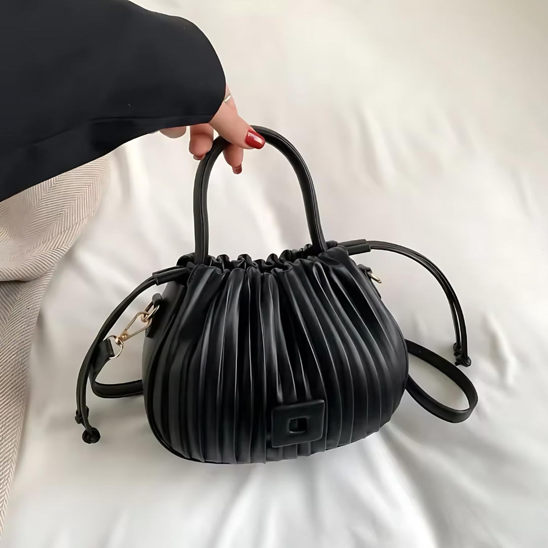 Frau hebt die schwarze Vintage Umhängetasche aus PU-Leder leicht am verstellbaren Schulterriemen an. Die elegante Tasche zeigt ihren luxuriösen Vintage-Stil und die großzügige Kapazität für vielseitige Nutzung.
