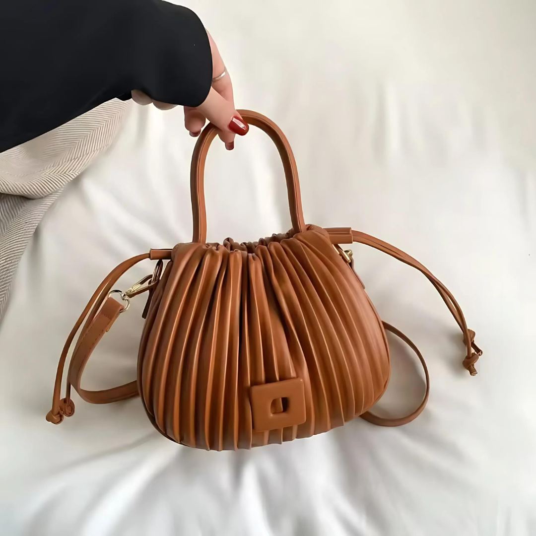 Frau hebt die camel Vintage Umhängetasche aus PU-Leder leicht am verstellbaren Schulterriemen an. Die elegante Tasche zeigt ihren luxuriösen Vintage-Stil und die großzügige Kapazität für vielseitige Nutzung.