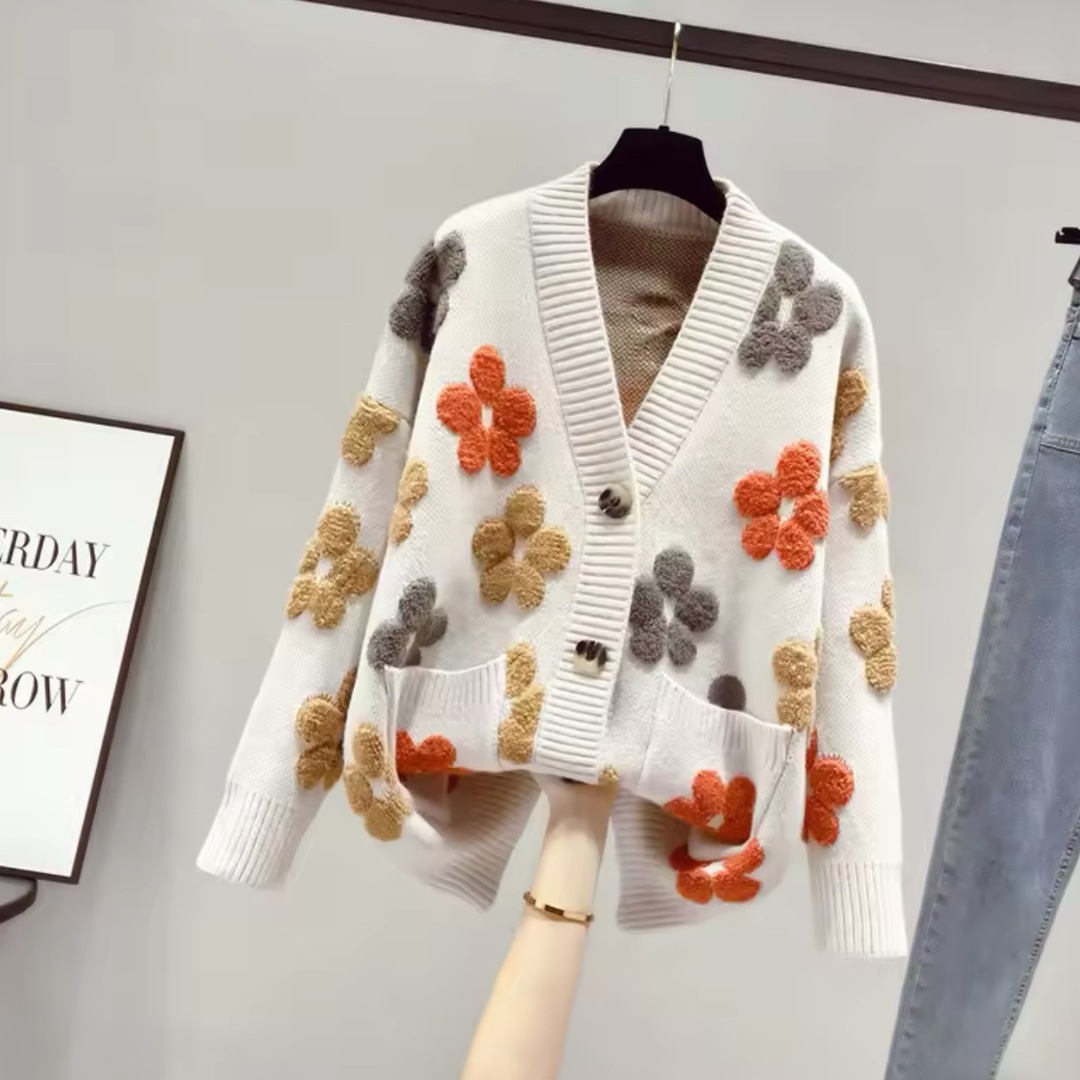 Produktfoto des eleganten Cardigans Flowers in Weiß, in Vorderansicht. Der Cardigan zeigt sich im lockeren, westlichen Stil mit langem Ärmel und femininen V-Ausschnitt, gefertigt aus weichem, hochwertigem Strickmaterial. Die entspannte Passform bietet Komfort und Wärme für die Herbstsaison und verleiht jedem Outfit eine herbstliche Eleganz