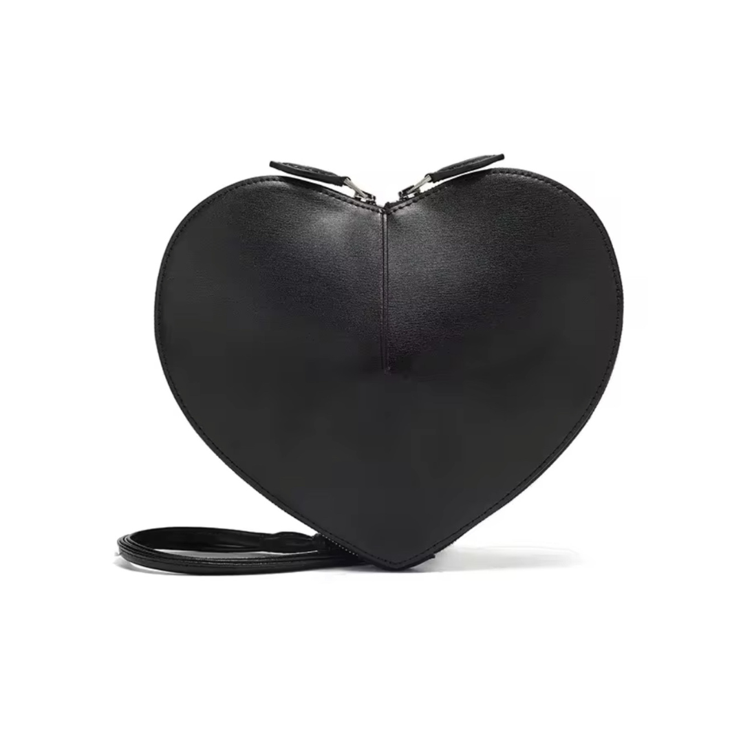 Tasche Heart in Schwarz auf neutralem Hintergrund. Die Umhängetasche im eleganten Herzdesign vereint trendigen Stil mit praktischer Funktionalität. Ideal für modebewusste Frauen, bietet diese Tasche Platz für Ihre Essentials und verleiht jedem Outfit eine coole, süße Note.