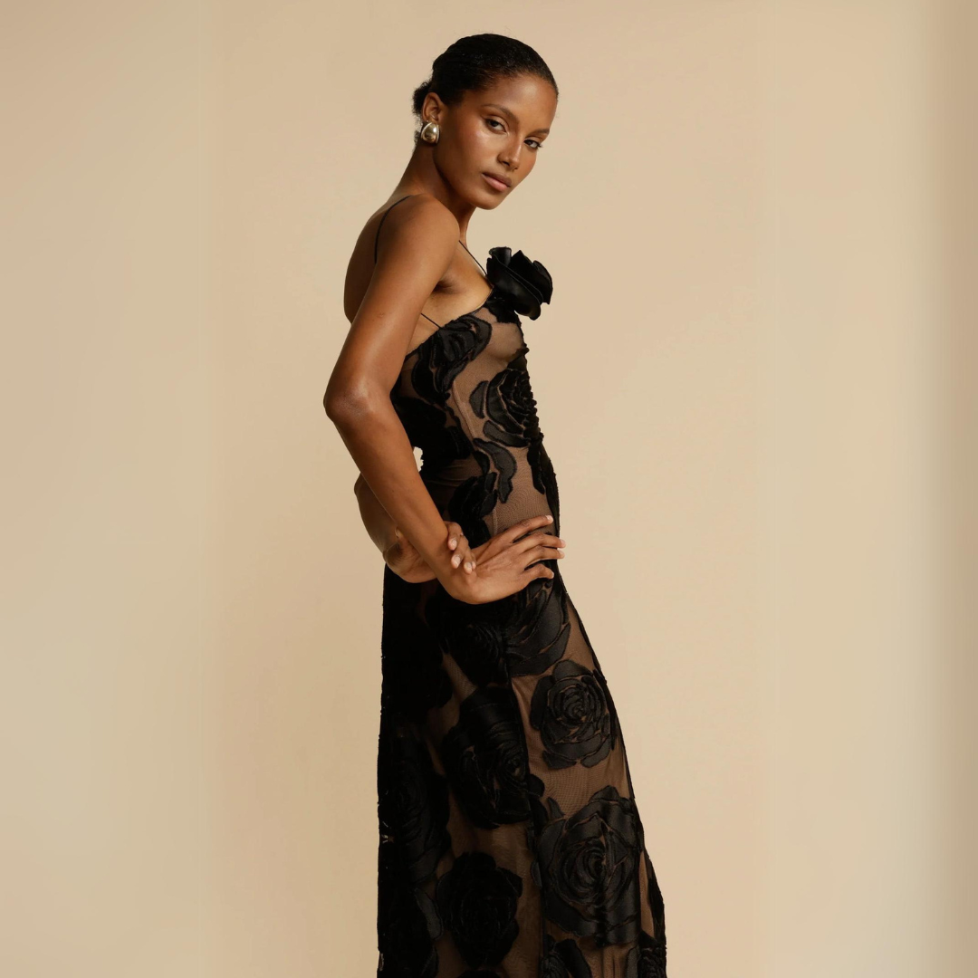 Seitenansicht des eleganten Kleid Mary, das eine stilvolle Ein-Schulter-Silhouette und eine figurbetonte Bodycon-Passform zeigt. Die hohe Taille und das zarte Blumenmuster betonen die schlanke Silhouette und Weiblichkeit. Getragen von einer Frau.