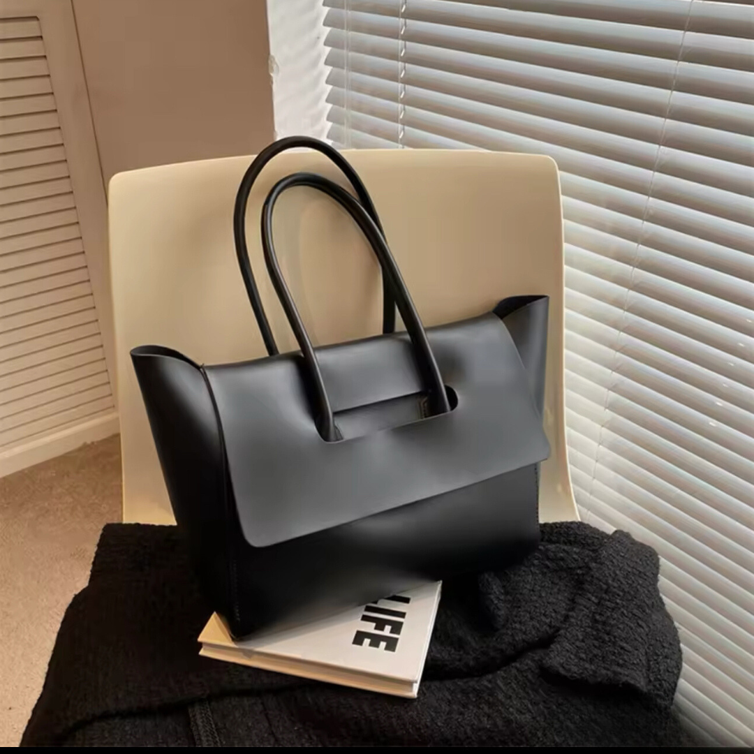 Vintage Shopper in Farbe Schwarz auf einem Stuhl – Die großzügige Tasche aus hochwertigem PU-Material steht stilvoll auf einem Stuhl, um ihr elegantes Vintage-Design und die praktische Kapazität zu präsentieren. Ideal für den täglichen Gebrauch und besondere Anlässe, zeigt die Tasche ihre luxuriöse Haptik und Vielseitigkeit.