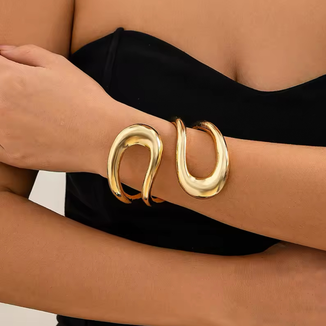 Goldfarbener Armreif, getragen von einer Frau, zeigt das elegante und robuste Design des Metallic Schmucksets. Der Armreif ist flexibel und passt sich bequem dem Handgelenk an, ideal für moderne und edgy Looks.