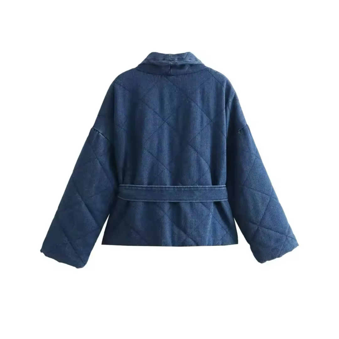 Denim Steppjacke Charly in Blau, Produktfoto in Rückansicht auf neutralem Hintergrund, gepolstertes Design mit Gürtel, ideal für Winter 2024.