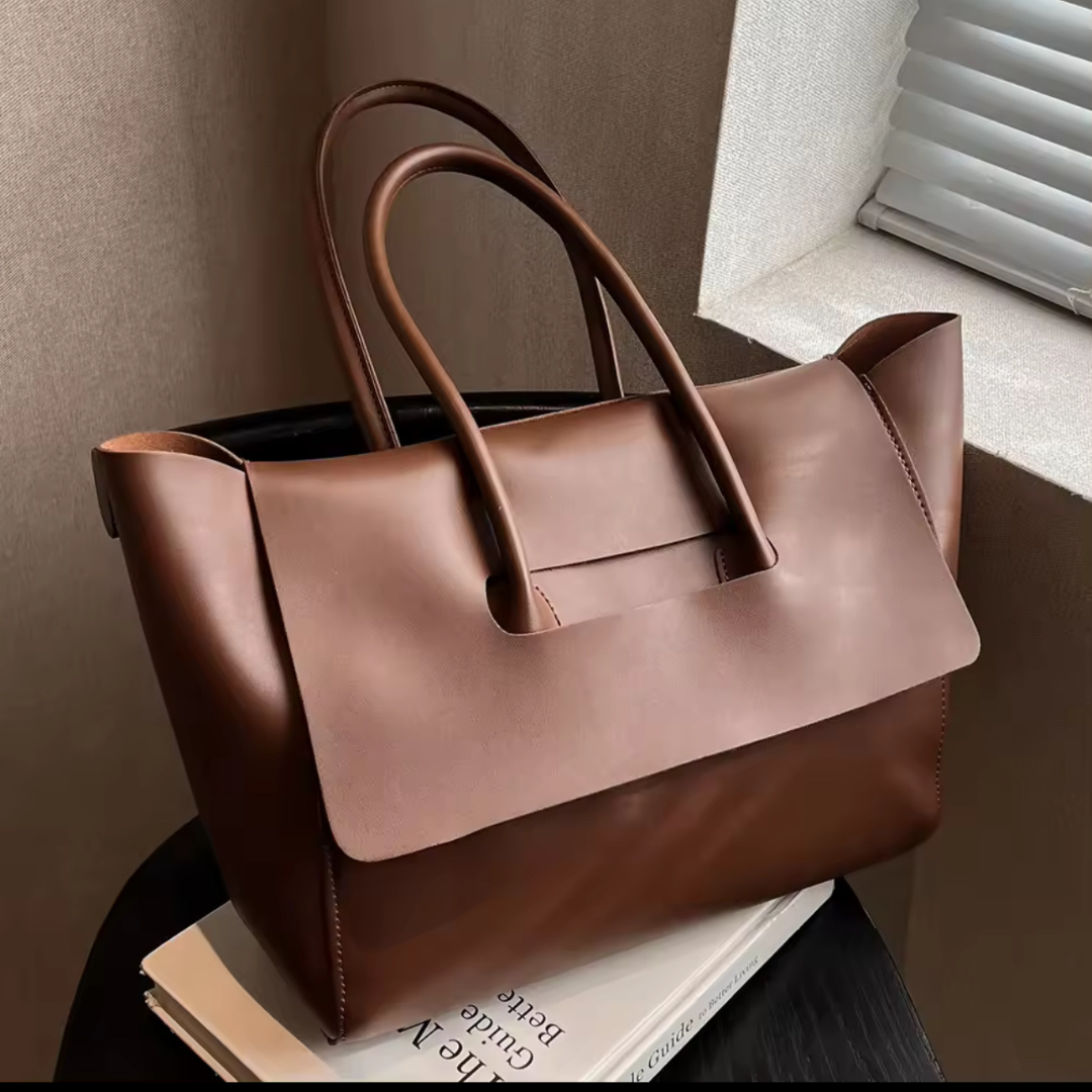 Vintage Shopper in Farbe Coffee auf einem Buch – Die elegante Tasche aus hochwertigem PU-Material liegt auf einem Buch, um ihr klassisches Vintage-Design und die großzügige Kapazität zu betonen. Das Bild zeigt die stilvolle Tasche in einer luxuriösen Farbe, ideal für den Alltag und besondere Anlässe.