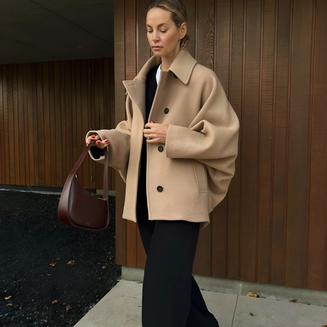 Der Vintage Wool Coat in Khaki, getragen von einer Frau in der Vorderansicht. Der klassische Einreiher-Mantel zeigt lässige Batwing-Ärmel und einen eleganten Reverskragen. Der hochwertige Wollstoff sorgt für Wärme und Komfort, während die lockere Passform einen stilvollen, vintage-inspirierten Look verleiht