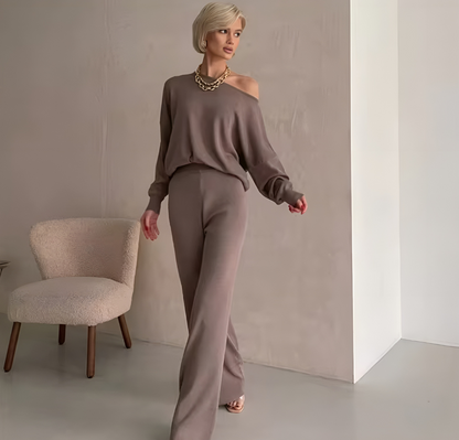 Frau in elegantem Cozy Set Irina in Khaki, bestehend aus einem schulterfreien, gestrickten Pullover und einer passenden Hose, in Vorderansicht. Das zweiteilige Set bietet hohen Komfort durch den weichen Strickstoff und kombiniert einen femininen, modernen Look mit einem trendigen Design. Ideal für Freizeit, Sport oder stilvolle Outfits unterwegs.