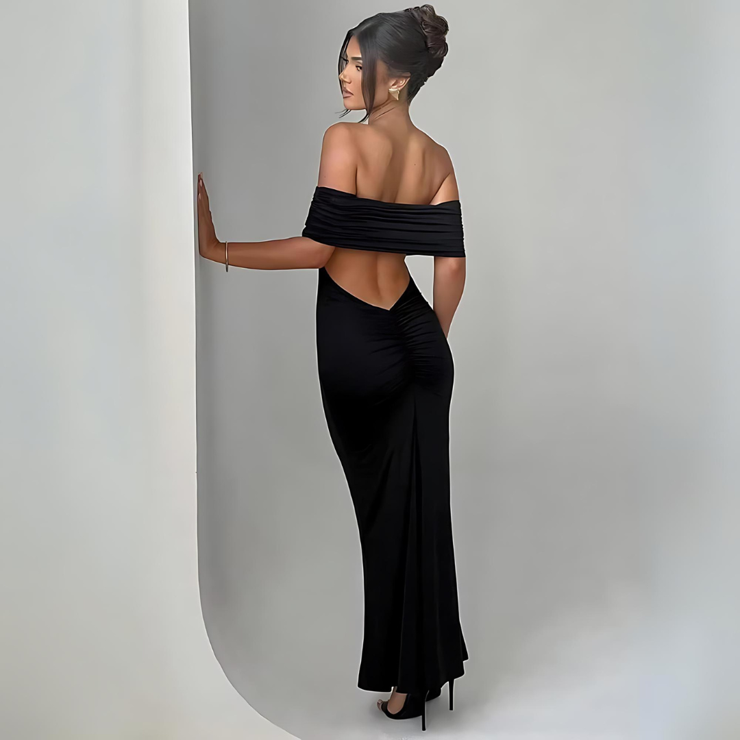 ückansicht des schwarzen Maxi-Kleids Sienna, getragen von einer Frau. Das Kleid zeigt sein schulterfreies, trägerloses und rückenfreies Design, das eine verführerische Silhouette betont. Ideal für elegante Events, Hochzeiten und Club-Partys.