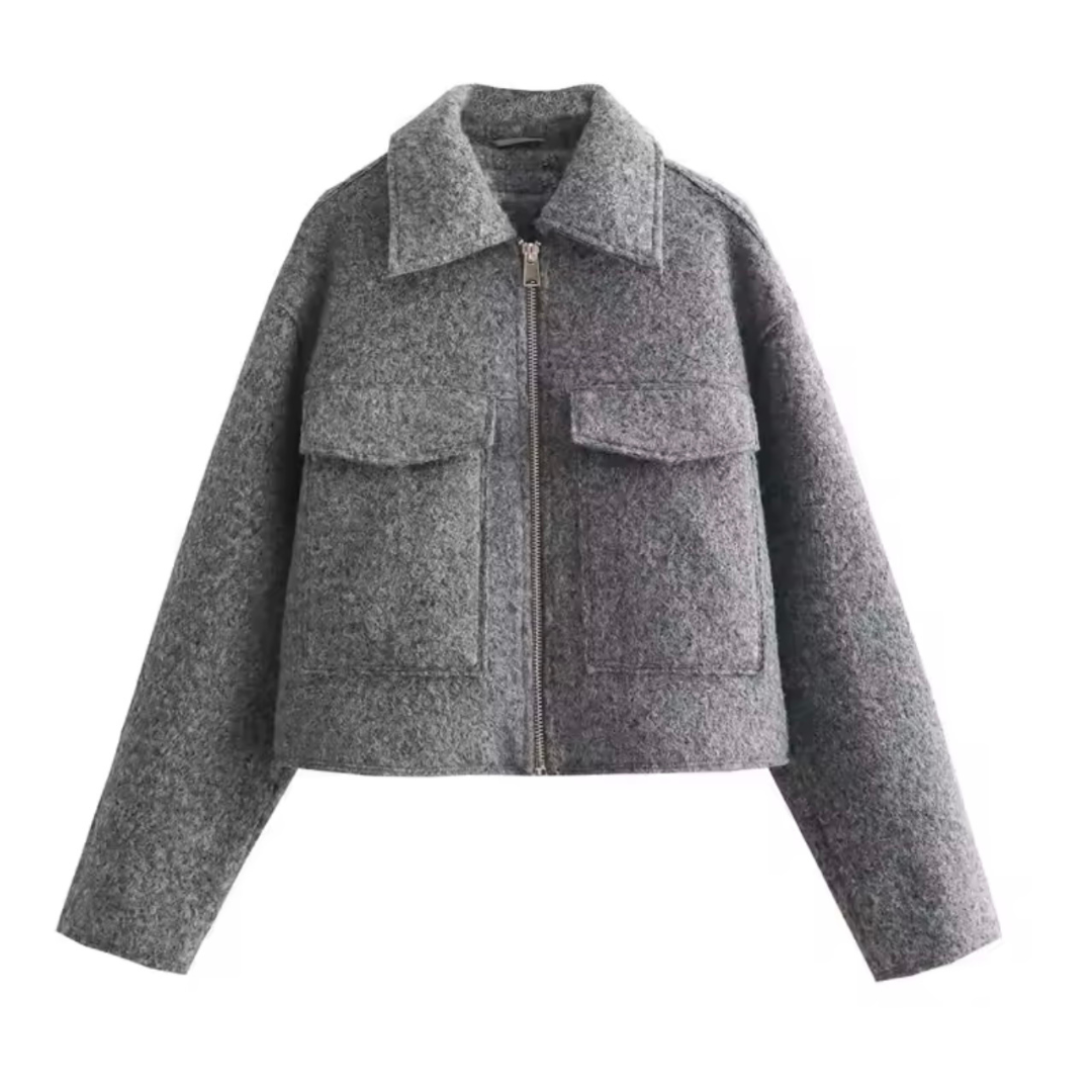 Die Cropped Jacket in der Vorderansicht. Die Jacke besteht aus klassischem Tweed-Stoff und hat einen modernen, verkürzten Schnitt. Der Reißverschluss ist deutlich sichtbar, und das hochwertige Material sorgt für Wärme und Komfort.