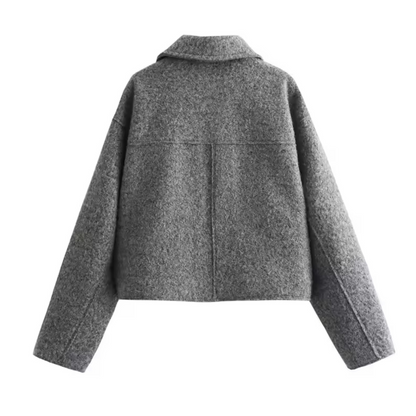 Die Cropped Jacket in der Rückansicht. Die Jacke zeigt den klassischen Tweed-Stoff und den eleganten Cropped-Schnitt. Der Reißverschluss ist im Rückenbereich sichtbar, und das hochwertige Material bietet eine stilvolle und warme Option für die Herbst- und Wintersaison.